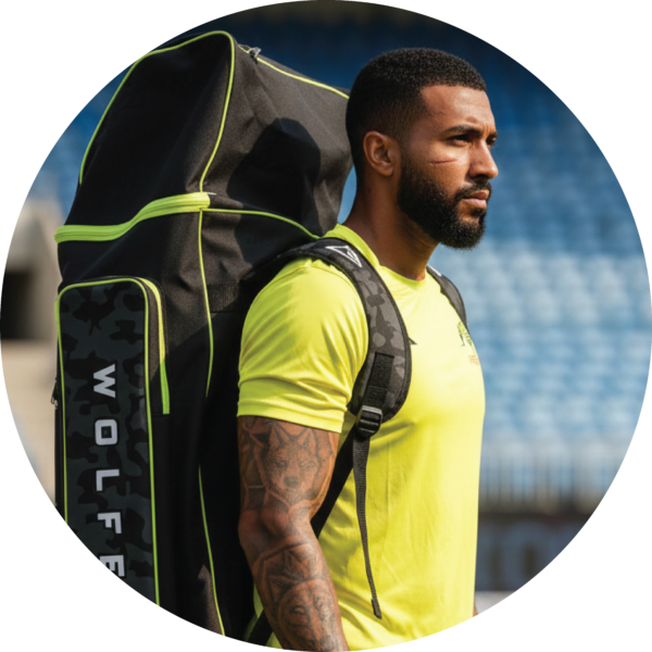 Cricketer carrying large black and lime green Wolfer cricket kit bag on shoulder, perfect for top order batsmen and wicketkeepers